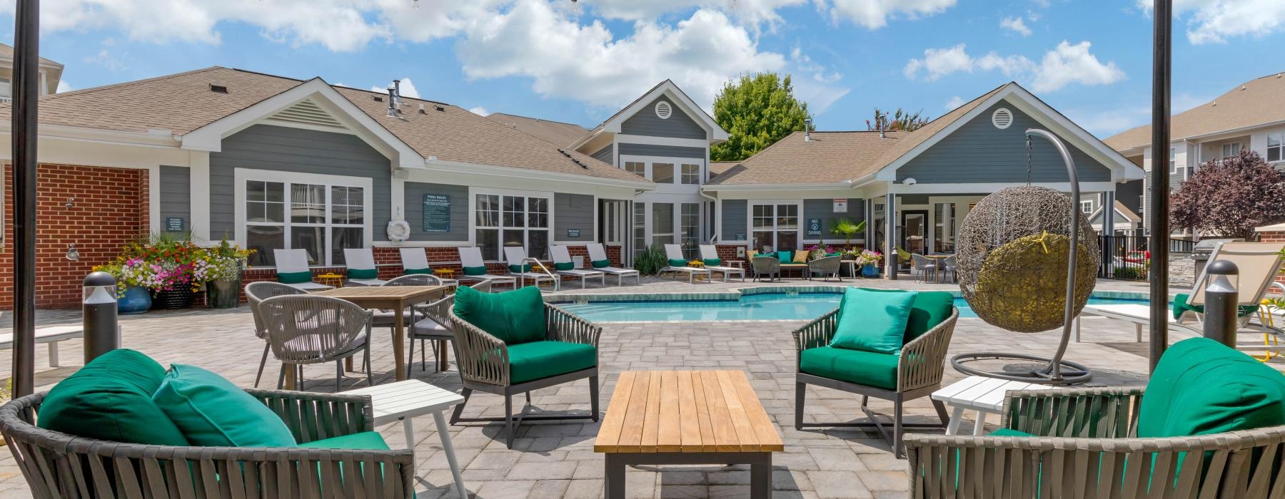 a patio with tables and chairs and a pool in the background