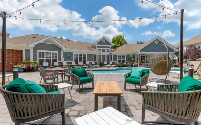 a patio with tables and chairs and a pool in the background